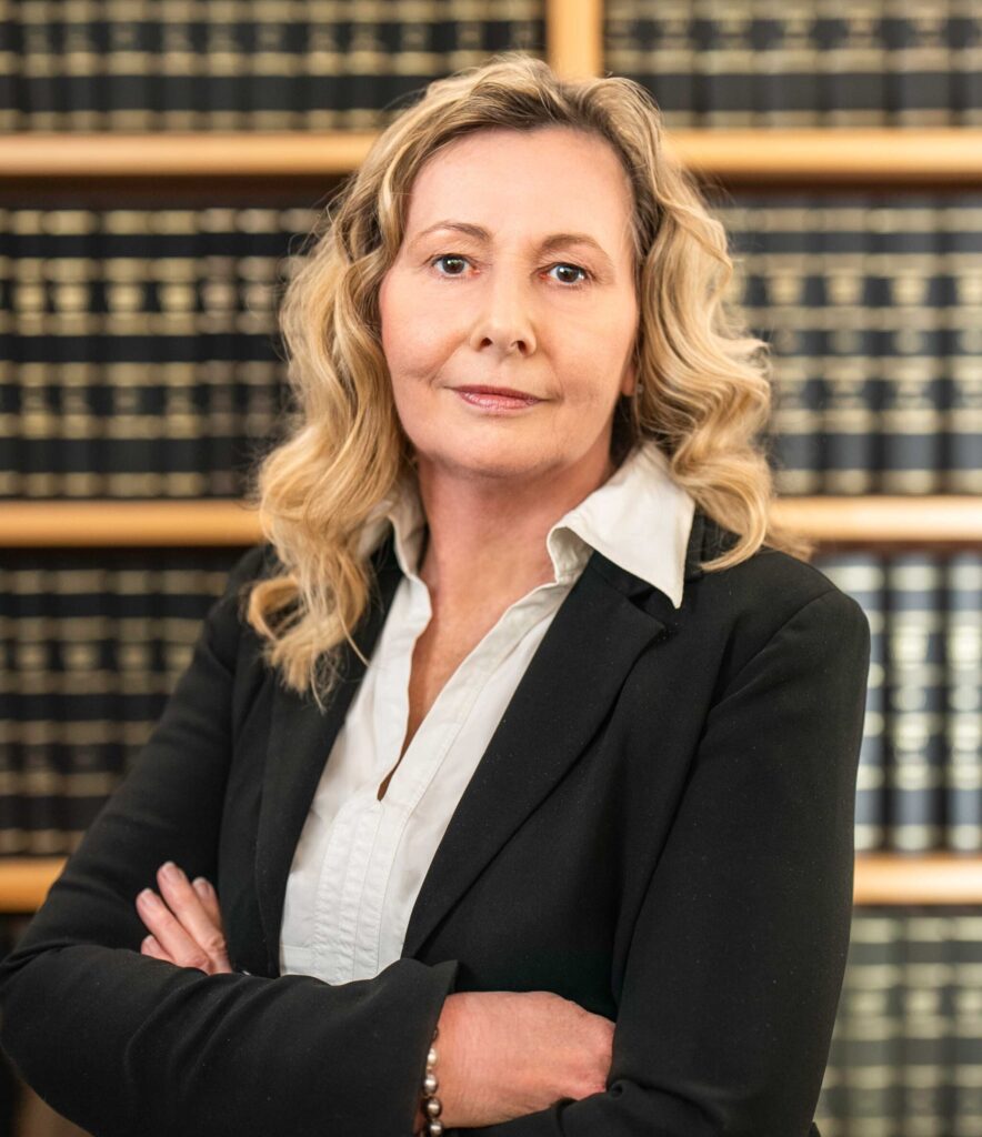 Porträt einer erfahrenen Rechtsanwältin und Wirtschaftsprüferin im schwarzen Blazer vor einem Bücherregal – Expertin für Rechtsberatung und Wirtschaftsprüfung im Norden